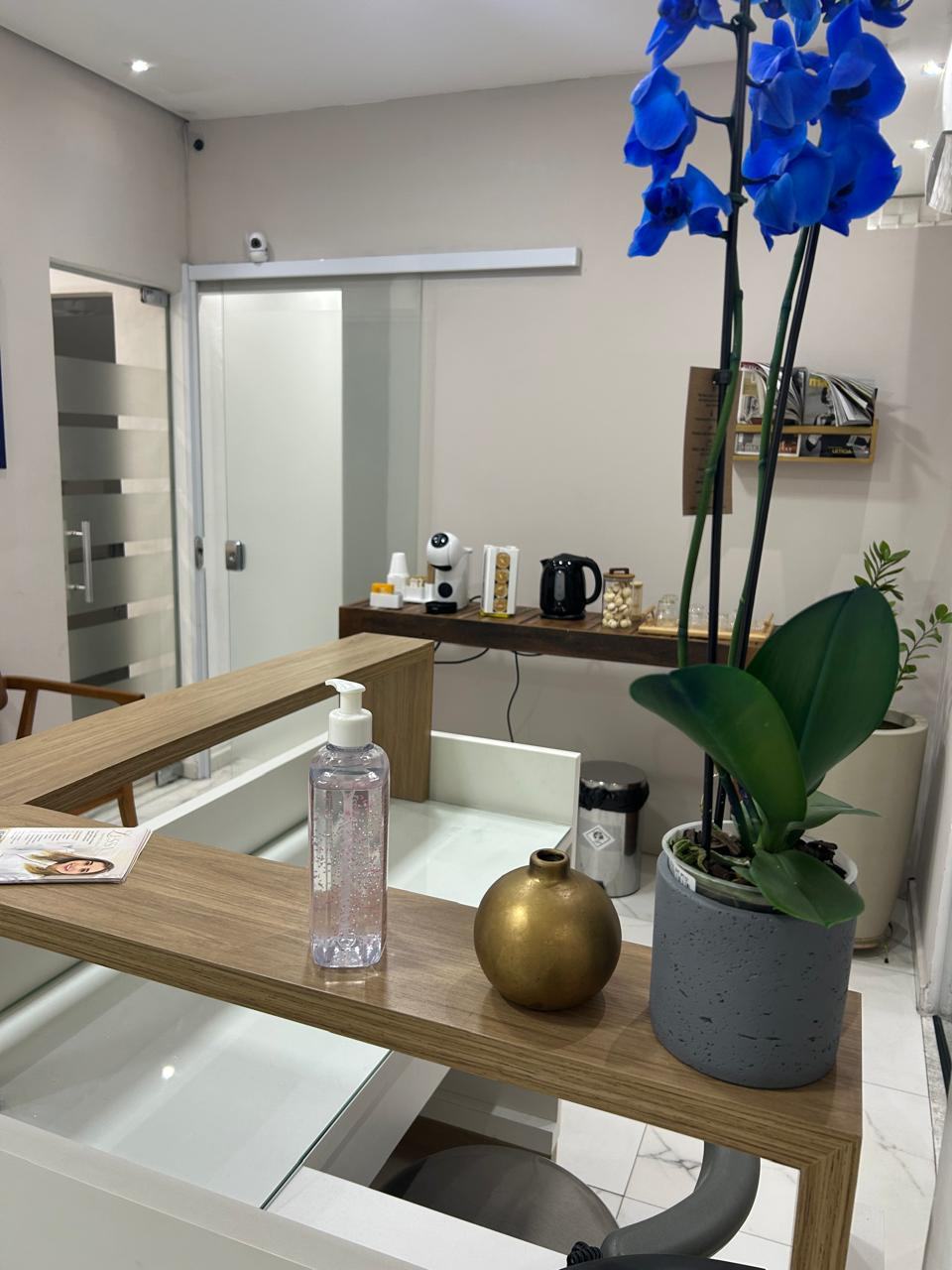 Mesa de café com cafeteira, chaleira, petiscos e uma orquídea azul na recepção