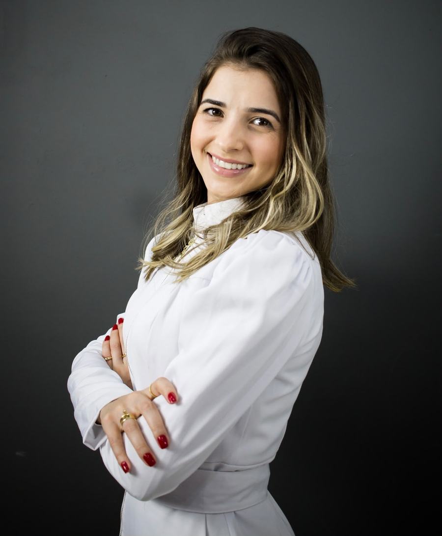 Retrato da Dra. Jéssica Lessa sorrindo, com jaleco branco